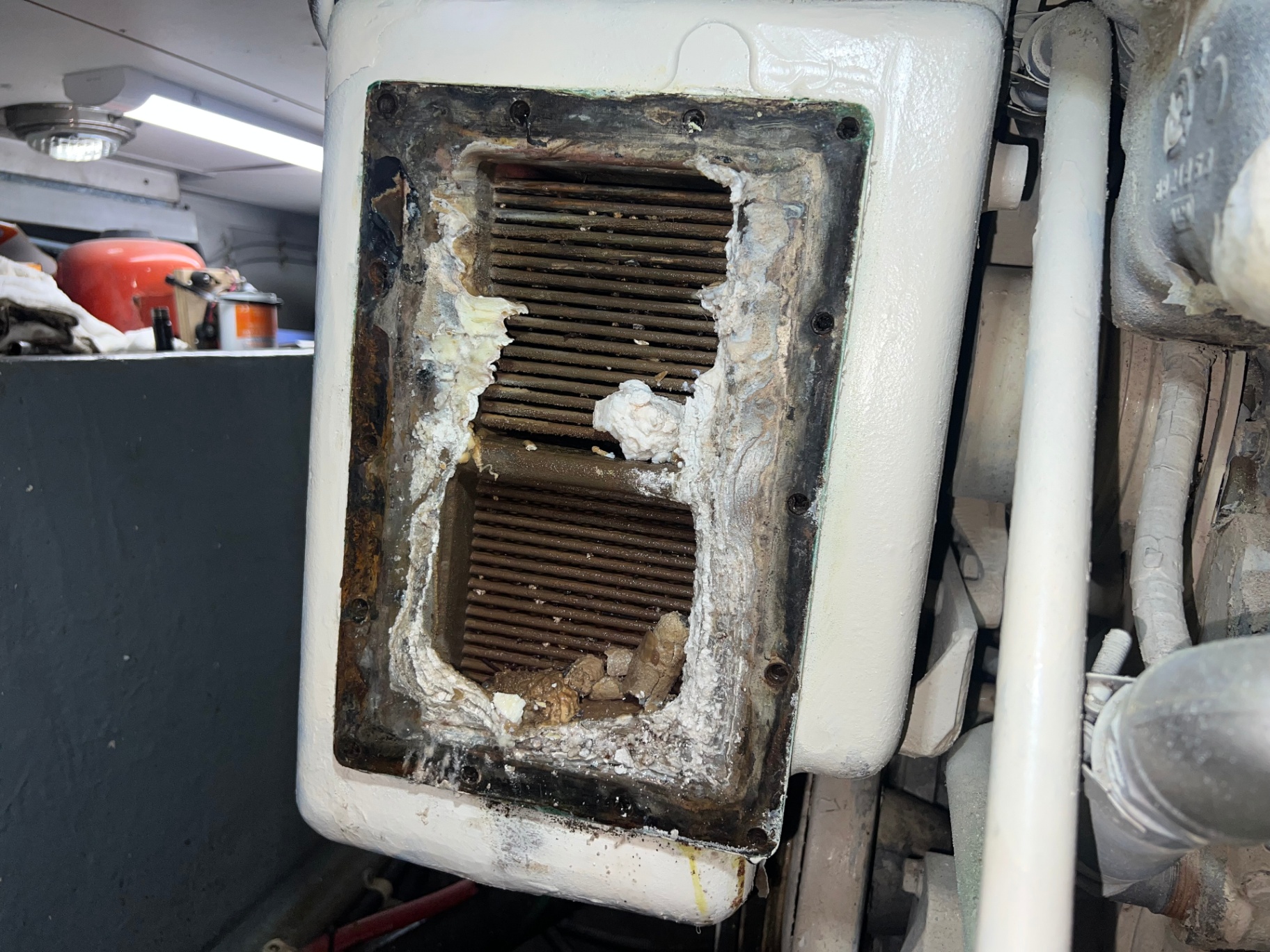 Heat exchanger end cap opened in the engine bay showing scale